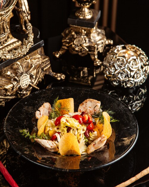 chicken salad with vegetables and potato chips in a plate